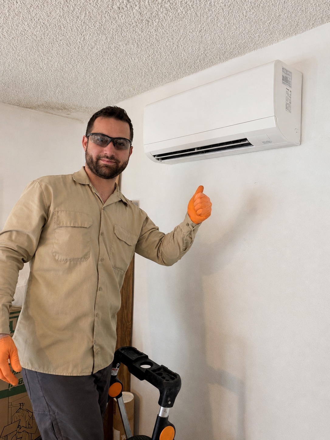 HVAC technician giving a thumbs up beside a mounted mini split