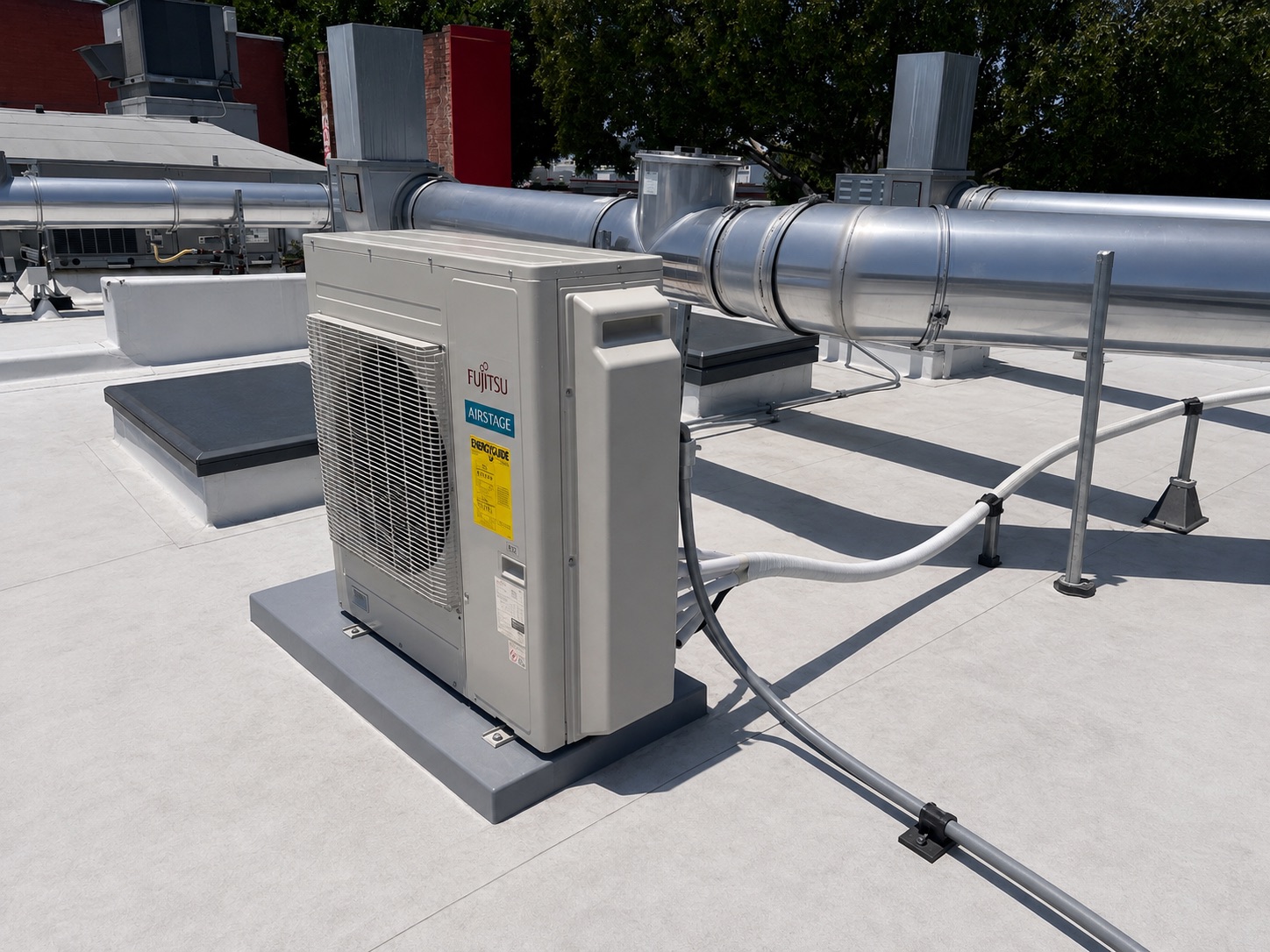Fujitsu outdoor HVAC unit beside commercial rooftop ventilation ductwork