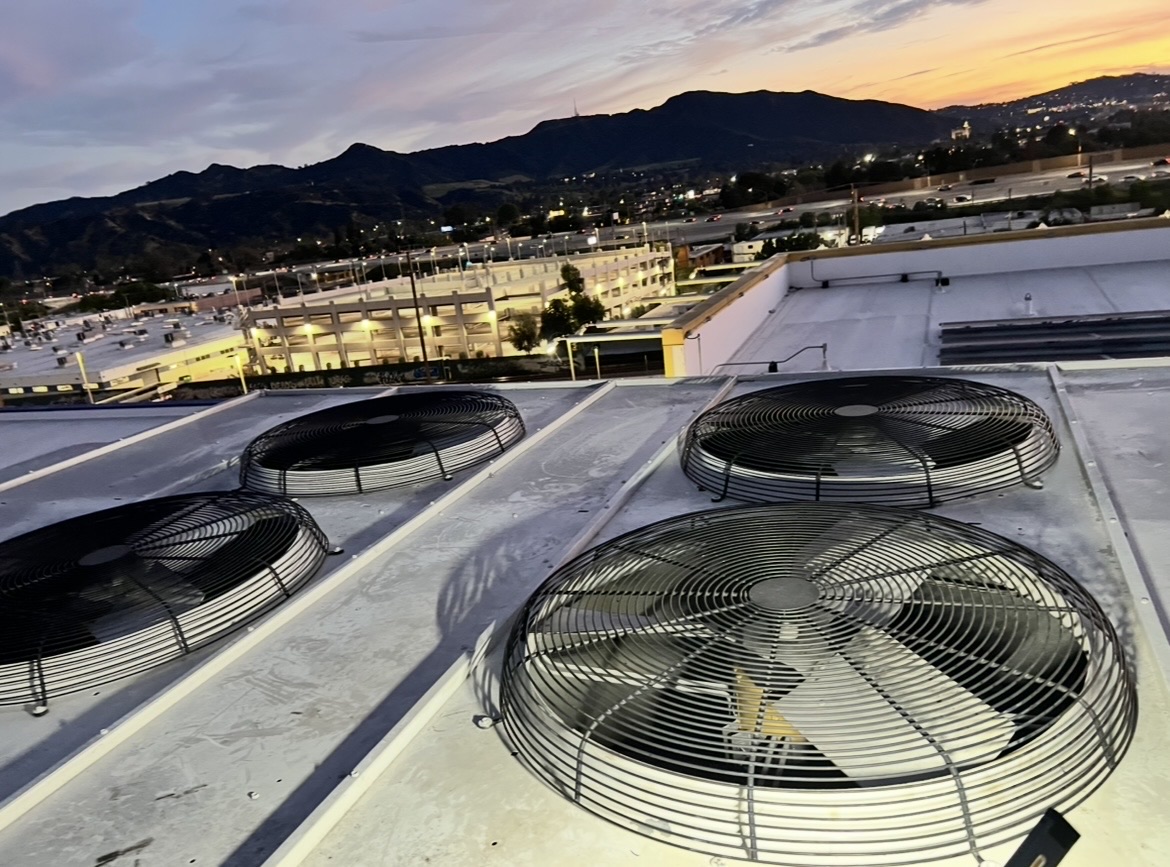 Commercial rooftop HVAC units at dusk with condenser fans visible